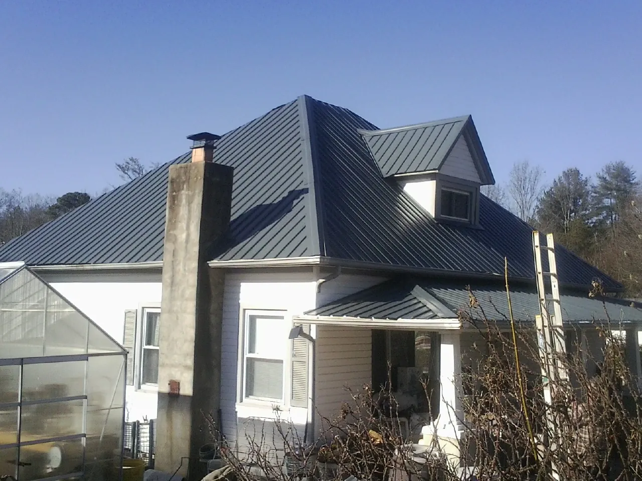 Dark blue standing seam metal roof on a white farmhouse with dormer — Slate & Tile Roof Repair by Roofing Brothers in Syracuse